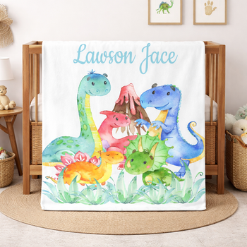Blanket with cartoon dinosaurs and 'Lawson Jace' text in a nursery setting